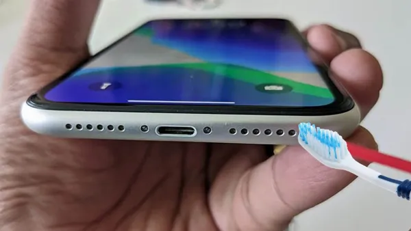 alt: Vệ sinh loa iPhone bằng dụng cụ mềm