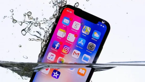 Hình ảnh một người đang cầm chiếc iPhone 13 bị ướt và dùng khăn mềm lau khô, minh họa cho việc cần lau khô điện thoại sau khi tiếp xúc với nước