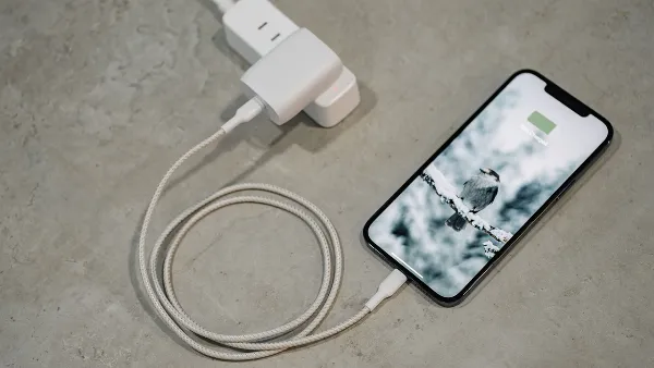 Một chiếc iPhone 13 Pro Max màu xanh dương đang được cắm sạc pin bằng bộ sạc chính hãng