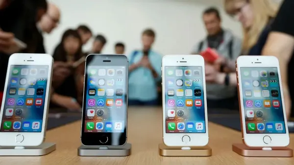 Một chiếc iPhone 6 màu xám đang được cầm trên tay, hiển thị màn hình chính với các biểu tượng ứng dụng