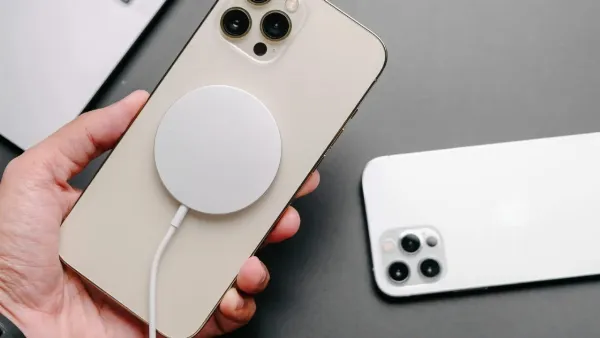 Một người đang vừa sạc pin iPhone bằng sạc MagSafe vừa sử dụng điện thoại